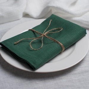 Hunter green linen napkin folded and tied with rustic natural twine, beautifully styled on a white ceramic plate. Elegant organic linen table textile designed for sustainable dining, modern table decor, intimate dinners, wedding receptions, farmhouse interiors and seasonal entertaining. Soft washed linen with a rich natural texture, reusable eco friendly cloth napkin for everyday meals, cottagecore styling, luxury tablescapes, holiday gatherings and timeless handmade home decor.