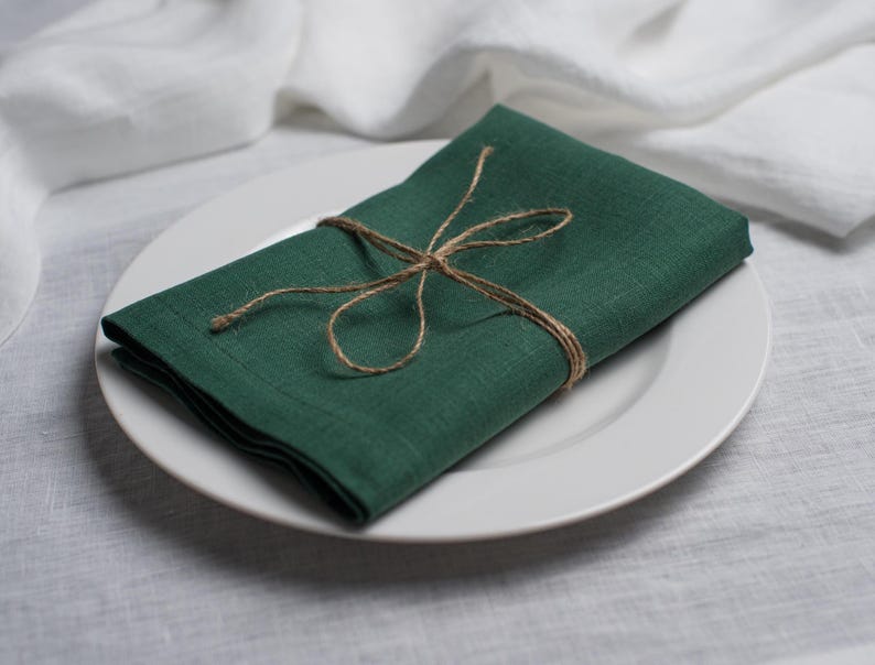 Hunter green linen napkin folded and tied with rustic natural twine, beautifully styled on a white ceramic plate. Elegant organic linen table textile designed for sustainable dining, modern table decor, intimate dinners, wedding receptions, farmhouse interiors and seasonal entertaining. Soft washed linen with a rich natural texture, reusable eco friendly cloth napkin for everyday meals, cottagecore styling, luxury tablescapes, holiday gatherings and timeless handmade home decor.