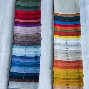 Organic linen napkins in different colors neatly folded in vertical stacks, showcasing a wide color palette for modern table styling and sustainable home decor. Soft washed linen fabric with natural texture, eco friendly reusable dinner napkins for weddings, hosting, farmhouse table settings, minimalist interiors, spring and summer entertaining, handmade table linens available in multiple shades including sage green, terracotta, mustard, blue, pink, lavender, natural beige and olive green.