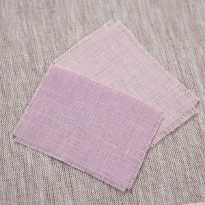 May include: Two squares of fabric in shades of pink, with a slightly darker pink on top. The fabric has a textured, woven appearance.
