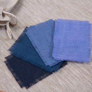 May include: Five fabric swatches in shades of blue, ranging from dark navy to light blue. The swatches are arranged in a fan shape and have a raw edge.