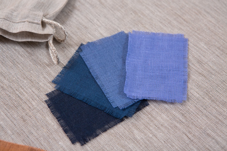 May include: Five fabric swatches in shades of blue, ranging from dark navy to light blue. The swatches are arranged in a fan shape and have a raw edge.