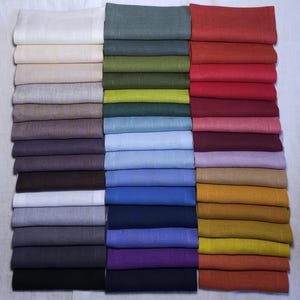 Organic linen napkins in different colors neatly folded in vertical stacks, showcasing a wide color palette for modern table styling and sustainable home decor. Soft washed linen fabric with natural texture, eco friendly reusable dinner napkins for weddings, hosting, farmhouse table settings, minimalist interiors, spring and summer entertaining, handmade table linens available in multiple shades including sage green, terracotta, mustard, blue, pink, lavender, natural beige and olive green.