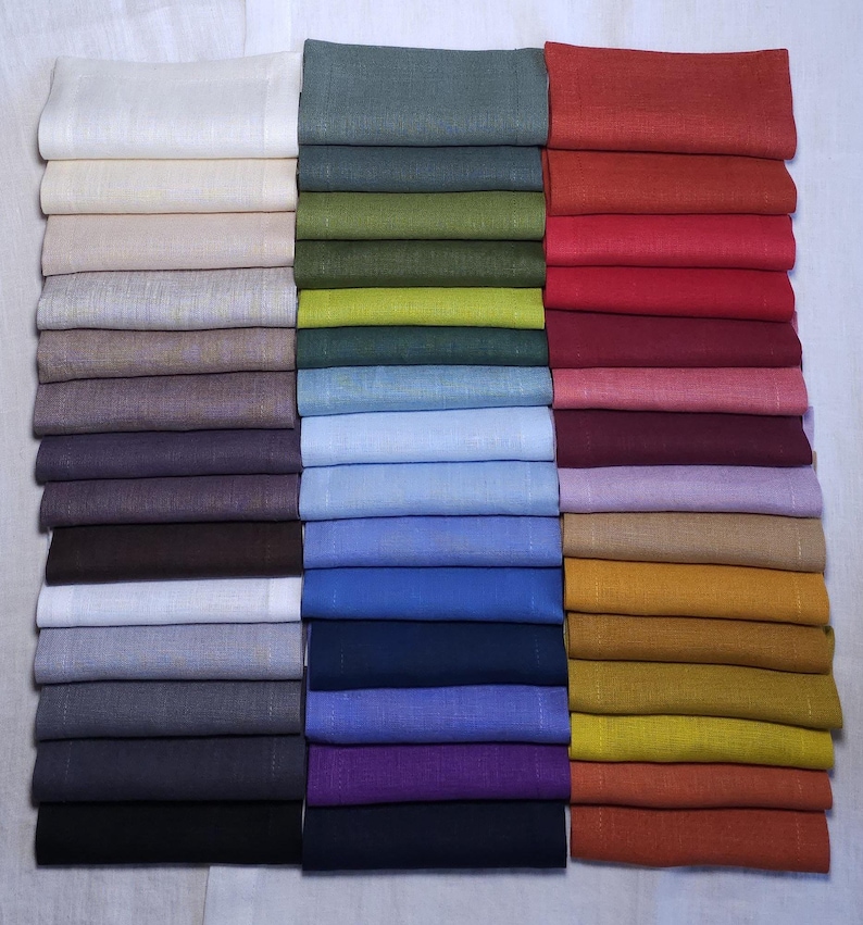 Organic linen napkins in different colors neatly folded in vertical stacks, showcasing a wide color palette for modern table styling and sustainable home decor. Soft washed linen fabric with natural texture, eco friendly reusable dinner napkins for weddings, hosting, farmhouse table settings, minimalist interiors, spring and summer entertaining, handmade table linens available in multiple shades including sage green, terracotta, mustard, blue, pink, lavender, natural beige and olive green.