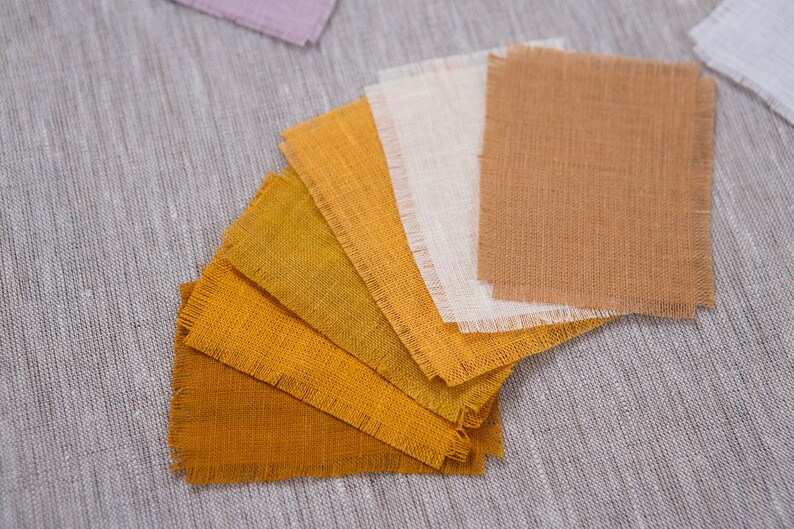 May include: A set of fabric swatches in various shades of yellow and brown, arranged in a fan shape. The swatches are made of a natural linen fabric with a slightly rough texture.