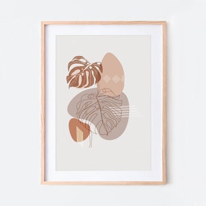 May include: A framed print with a minimalist design featuring brown and white abstract shapes and line drawings of tropical leaves on a light beige background.