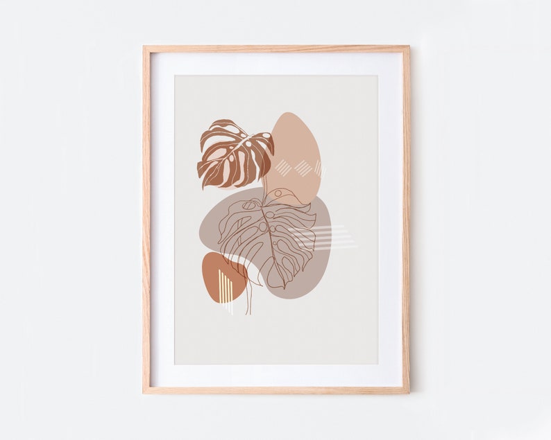 May include: A framed print with a minimalist design featuring brown and white abstract shapes and line drawings of tropical leaves on a light beige background.