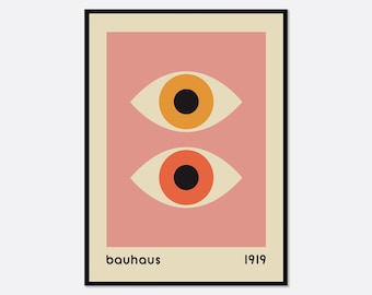 May include: A rectangular wall art print featuring a dusty pink background with two stylised eyes stacked vertically. The top eye has a yellow iris and the bottom eye has an orange iris. Both have black pupils. The text "bauhaus" and "1919" appear below.