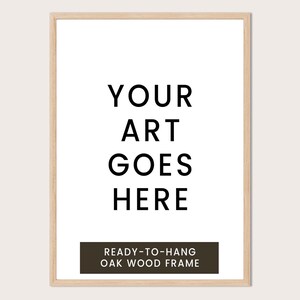 a simple, minimalist design with the text "YOUR ART GOES HERE" in a bold, black font. Below the text, there is a smaller caption that reads "READY-TO-HANG OAK WOOD FRAME".
