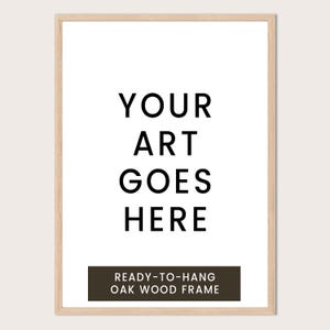 a simple, minimalist design with the text "YOUR ART GOES HERE" in a bold, black font. Below the text, there is a smaller caption that reads "READY-TO-HANG OAK WOOD FRAME".
