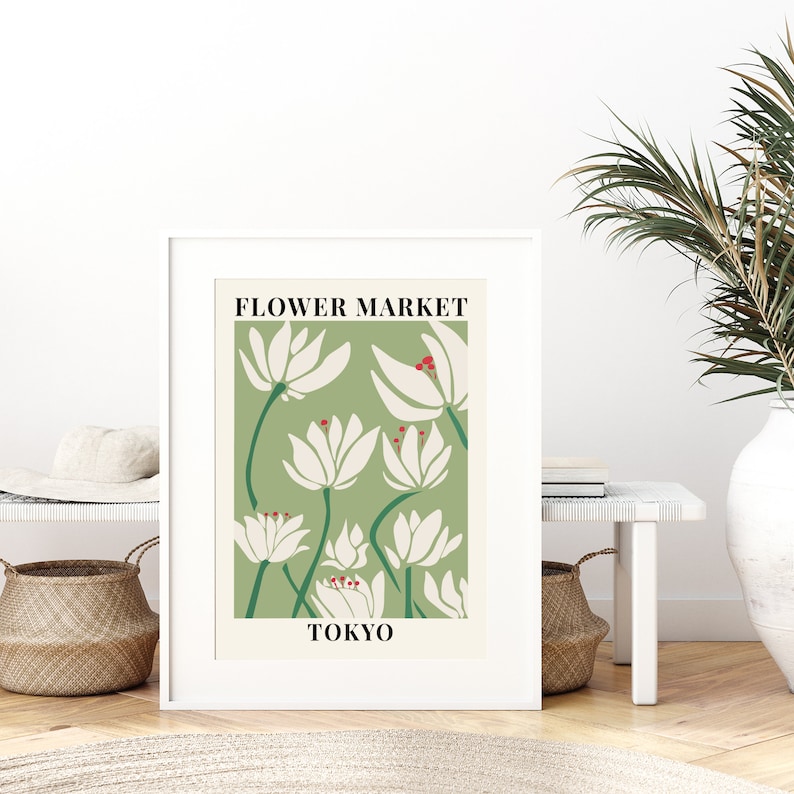 Puede incluir: Una impresi&oacute;n enmarcada en blanco con un fondo verde y flores estilizadas blancas. El texto "FLOWER MARKET TOKYO" est&aacute; impreso en negro en la parte superior e inferior de la impresi&oacute;n.