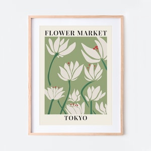 Puede incluir: Un p&oacute;ster enmarcado con fondo verde y flores blancas estilizadas. El texto "FLOWER MARKET TOKYO" est&aacute; impreso en el p&oacute;ster.