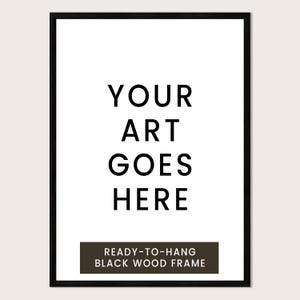 a black and white text-based design with the phrase "YOUR ART GOES HERE" prominently displayed. Below the main text, there is a smaller text that reads "READY-TO-HANG BLACK WOOD FRAME".