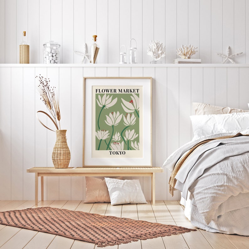 Puede incluir: Un p&oacute;ster enmarcado con fondo verde y flores blancas estilizadas. El p&oacute;ster dice "FLOWER MARKET TOKYO". El p&oacute;ster est&aacute; colgado en una pared blanca sobre un banco de madera y una alfombra marr&oacute;n.