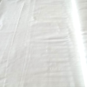 May include: A white, smooth, and wrinkle-free fabric with a subtle, striped pattern. The fabric is evenly lit and appears to be made of a high-quality material.