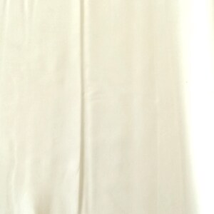 May include: A plain, off-white fabric swatch. The fabric has a smooth, slightly textured surface.