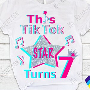 Pu&ograve; includere: Maglietta bianca con un design rosa e blu che dice "This Tik Tok Star Turns 7". Il design include una stella argentata glitterata, note musicali e una corona rosa.