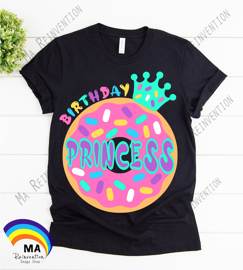 May include: Black t-shirt with a donut graphic and the text "Birthday Princess" in colorful letters. A crown with sprinkles is on top of the donut.