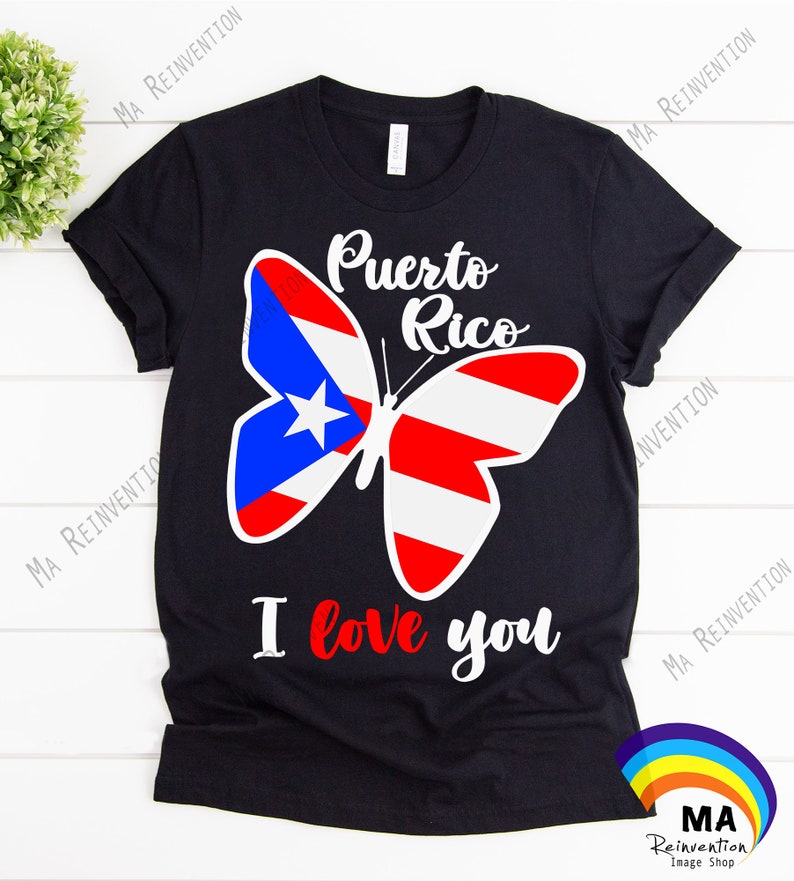 May include: Black t-shirt featuring a white butterfly design. The butterfly's wings are patterned with the colours of the Puerto Rican flag: red, white, and blue. The text "Puerto Rico" is above the butterfly and "I love you" is below it.
