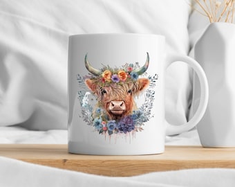 Könnte beinhalten: Weiße Keramiktasse mit einer Aquarell-Illustration einer braunen und weißen Kuh mit einer Blumenkrone. Die Blumen sind in den Farben Rosa, Blau, Lila und Gelb.