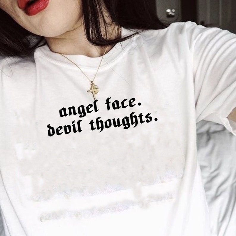 May include: White t-shirt with black text that reads "angel face. devil thoughts."