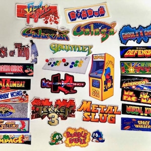 Könnte beinhalten: Eine Sammlung farbenfroher Arcade-Spiel-Aufkleber mit Titeln wie "Final Fight", "Galaxian", "Mortal Kombat" und "Space Invaders". Die Aufkleber zeigen lebendige Grafiken und Logos aus klassischen Videospielen.