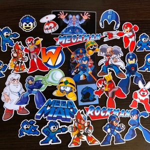 May include: A collection of colorful Mega Man stickers featuring various characters and logos from the video game series. The stickers showcase characters in action poses and pixelated designs, with the "Mega Man" and "Rockman" logos.