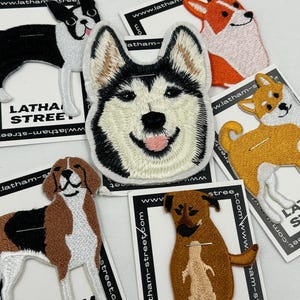 May include: A set of embroidered iron-on patches featuring various dog breeds. The patches are white, black, brown, orange, and yellow. The patches feature the text "Latham Street" and a website address.