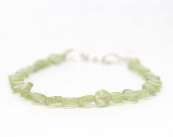 May include: A green gemstone bracelet with a silver clasp. The bracelet is made of small, irregular shaped stones.