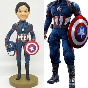 May include: A custom bobblehead figurine of a person dressed as Captain America. The figurine is holding a miniature Captain America shield and helmet. The figurine is standing on a brown base. The image also shows a full-body view of a Captain America action figure.