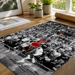May include: A rectangular poster featuring a black and white photograph of a basketball game in progress. A player in a red jersey with the number 23 is captured mid-air near the hoop, while the surrounding crowd is rendered in monochrome.