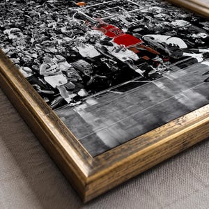May include: A framed wall art print featuring a black and white photograph of a basketball game with a crowd in the background. A player in a red jersey is jumping toward the hoop. The frame is made of dark, distressed wood with gold tones.