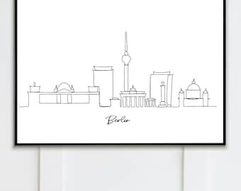 May include: Black framed art print featuring a minimalist line drawing of the Berlin skyline. The artwork includes iconic landmarks such as the Brandenburg Gate and the TV Tower, with the city name written below.