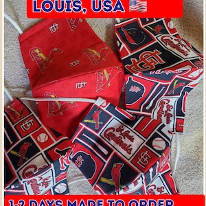 May include: Four handmade face masks featuring a red, white, and black St. Louis Cardinals pattern. The masks are made to order and ship within 1-2 days. "HANDMADE IN ST. LOUIS, USA" is written at the top of the image.