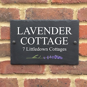 May include: Black slate house sign with white text that reads "Lavender Cottage" and "7 Littledown Cottages". A small purple lavender flower is depicted in the bottom right corner.
