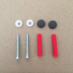 Puede incluir: Dos tacos de pared de plástico blanco, dos tacos de pared de plástico negro, dos tornillos plateados y dos tacos de pared de plástico rojo.