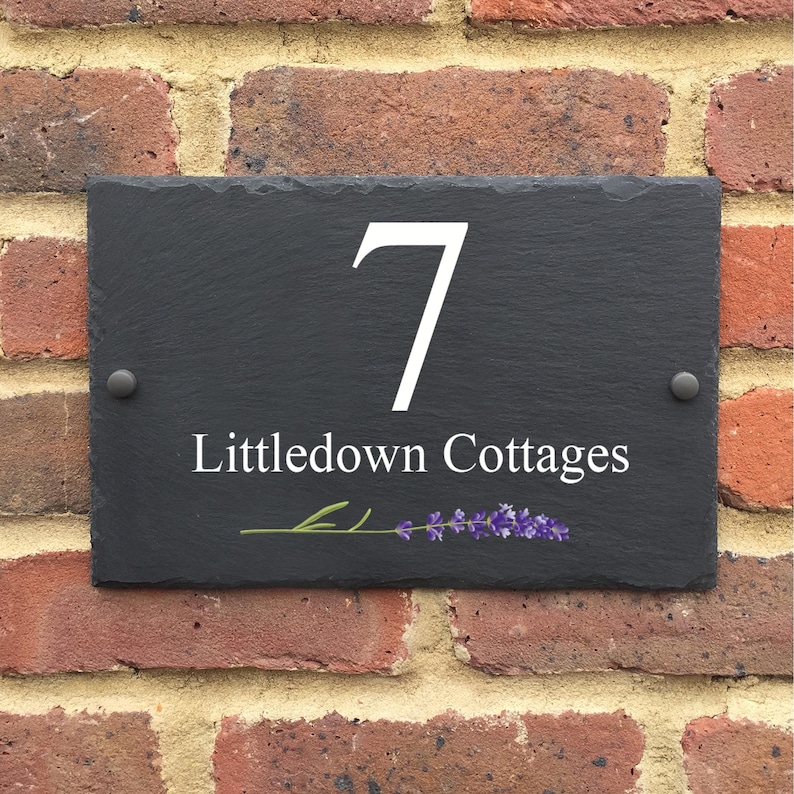 May include: Black slate house number sign with white lettering. The number 7 and the text "Littledown Cottages" are displayed on the sign. A small lavender sprig is depicted below the text.