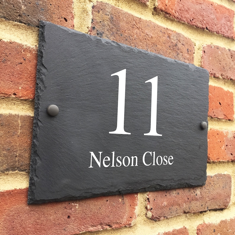 May include: Black slate house number sign with white lettering. The number 11 and the street name "Nelson Close" are displayed on the sign.