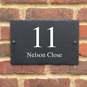 May include: Black slate house number sign with white lettering. The number 11 and the street name "Nelson Close" are displayed on the sign.