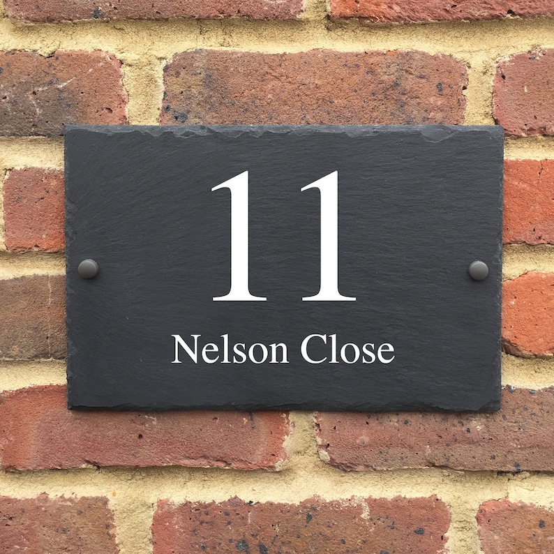 May include: Black slate house number sign with white lettering. The number 11 and the street name "Nelson Close" are displayed on the sign.