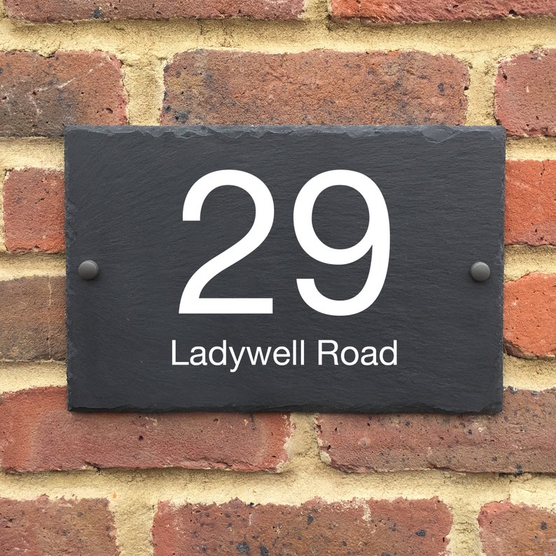 May include: A black slate house number sign with white lettering. The number 29 is displayed with the street name "Ladywell Road" underneath.