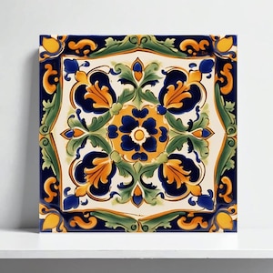 May include: Square ceramic tile with a floral design. The tile features a central blue flower surrounded by orange and blue floral elements, green leaves, and a white background. The border is dark blue and yellow.