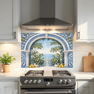 Può includere: Un paraschizzi da cucina con un design mediterraneo. L'opera d'arte raffigura alberi di limoni, un mare blu e una cornice architettonica ad arco. La tavolozza dei colori comprende blu, giallo e bianco, creando un'estetica luminosa.