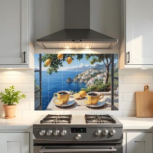 Puede incluir: Un protector contra salpicaduras de cocina con una vista panorámica de un pueblo costero con un mar azul y limones. Dos tazas de té amarillas con café y rodajas de limón están sobre una mesa. La escena está enmarcada por una ventana y un limonero.
