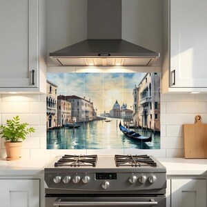 May include: A kitchen backsplash featuring a watercolor painting of a Venetian canal scene. The artwork depicts buildings along the water, gondolas, and a domed church under a sunset sky. The backsplash is installed above a stainless steel gas range.
