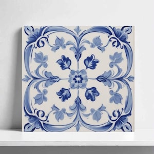 Pode incluir: Azulejo cerâmico quadrado com fundo branco e um design floral azul simétrico. O design apresenta flores e folhas estilizadas em tons variados de azul, criando um padrão decorativo clássico. O azulejo é provavelmente para decoração de casa.