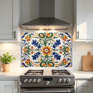 May include: A decorative kitchen backsplash with a floral pattern above a gas hob. The design features orange, blue, and green flowers on a white background. The kitchen has white cabinets and a stainless steel extractor fan.