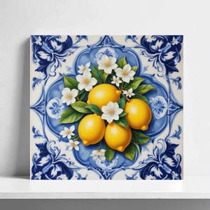 Op de afbeelding: Vierkant canvas kunstwerk met een stilleven van citroenen, witte bloesems en groene bladeren. Het kunstwerk is geplaatst tegen een blauw en wit patroon, dat doet denken aan traditionele tegelontwerpen. De citroenen zijn heldergeel.