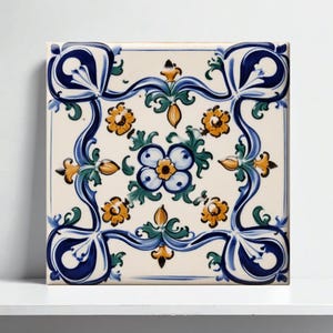 以下が含まれることがあります： 花柄のデザインが施された正方形のセラミックタイル。タイルは、青、黄、緑の花柄モチーフの繰り返し模様のクリーム色の背景が特徴です。境界線は濃い青色で、様式化された花柄のデザインです。