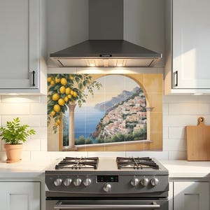 Puede incluir: Un salpicadero de cocina con un mural que representa una ciudad costera italiana. La obra de arte incluye un limonero y una ventana arqueada con vistas al mar y a los edificios de la ladera. El salpicadero está instalado sobre una cocina de gas de acero inoxidable.